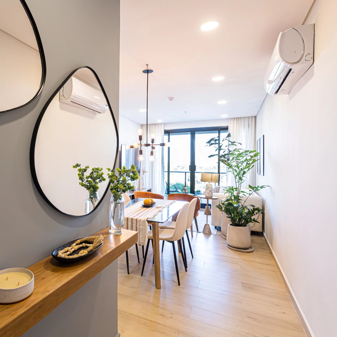 Entrée d’un appartement meublé avec miroir, console et salle à manger lumineuse dans l’immeuble Imagina Ycua Satí à Asunción, Paraguay.