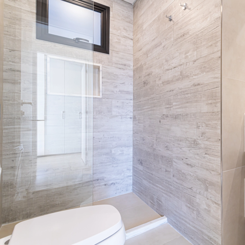 Douche à l’italienne avec paroi vitrée et revêtement effet pierre dans un appartement de l’immeuble Imagina Ycua Satí à Asunción, Paraguay.