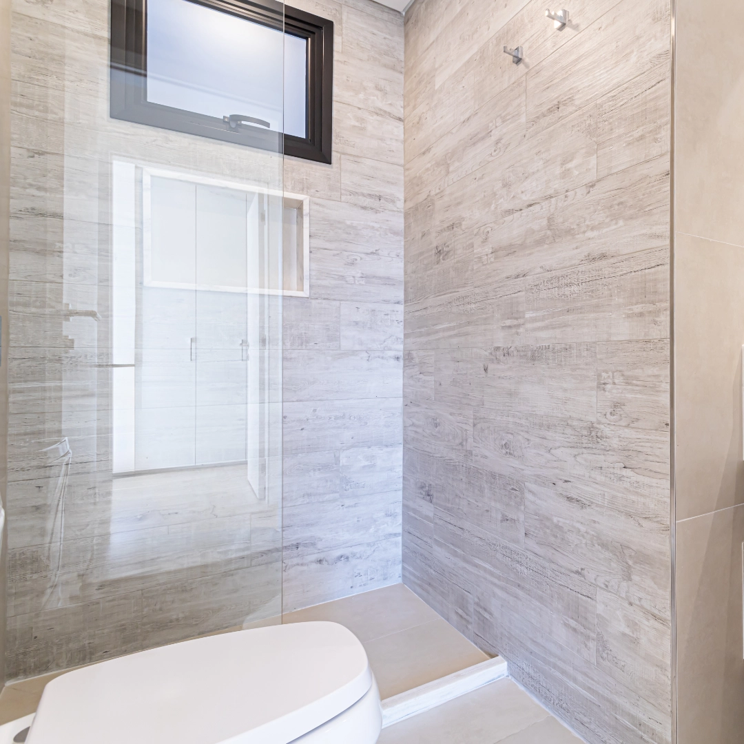 Douche à l’italienne avec paroi vitrée et revêtement effet pierre dans un appartement de l’immeuble Imagina Ycua Satí à Asunción, Paraguay.