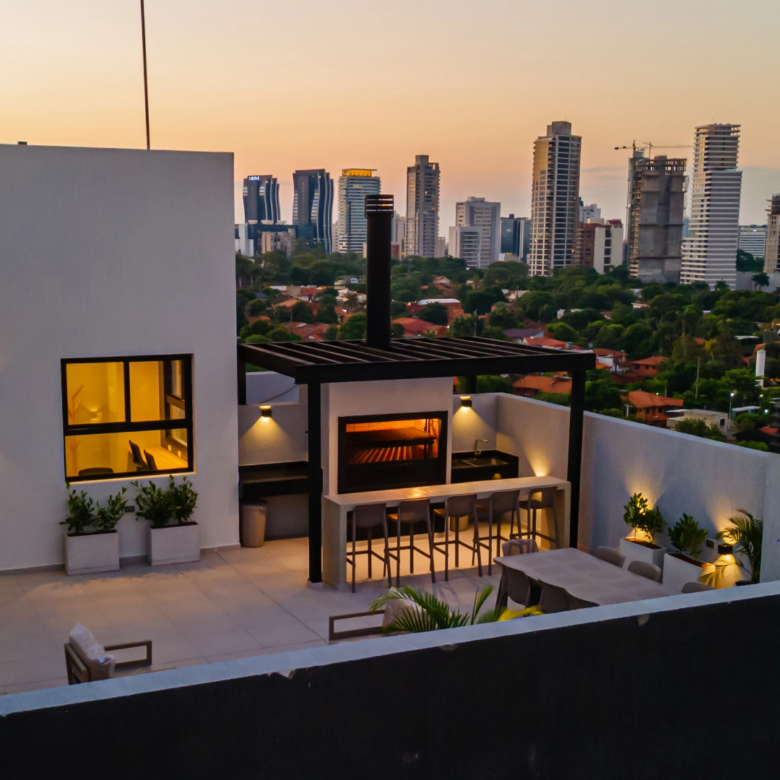 Quincho extérieur avec barbecue et vue sur les tours de la ville au crépuscule, sur le toit de l’immeuble Imagina Ycua Satí à Asunción, Paraguay.