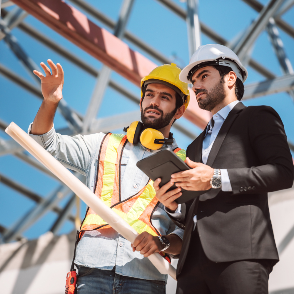 Civil engineer and construction worker manager holding digital tablet and blueprints , talking and planing about construction site.  Cooperation teamwork concept.