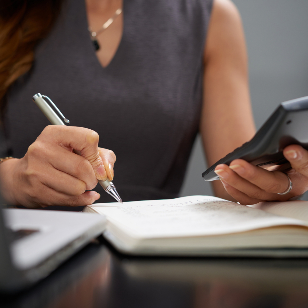 Close-up image of business lady making calculations and taking notes